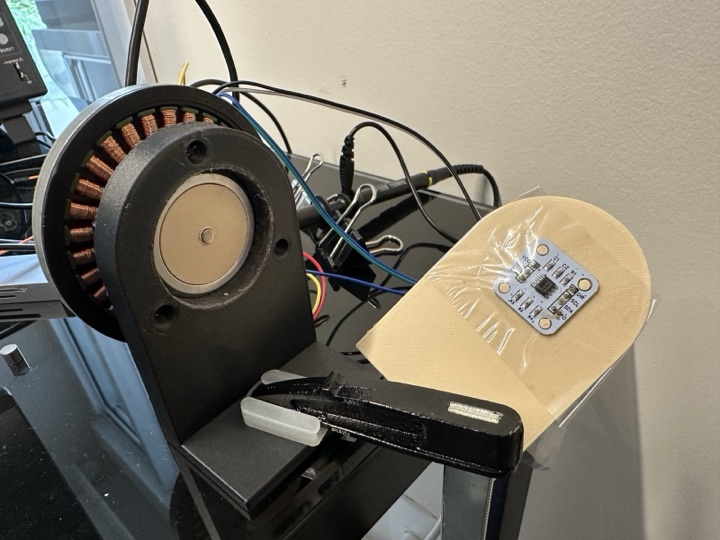 Top-down view of the motor with the rotor lifted off, showing the AS5600 PCB seated on the printed plate facing the new magnet holder, the magnet now visibly centred on the rotation axis.